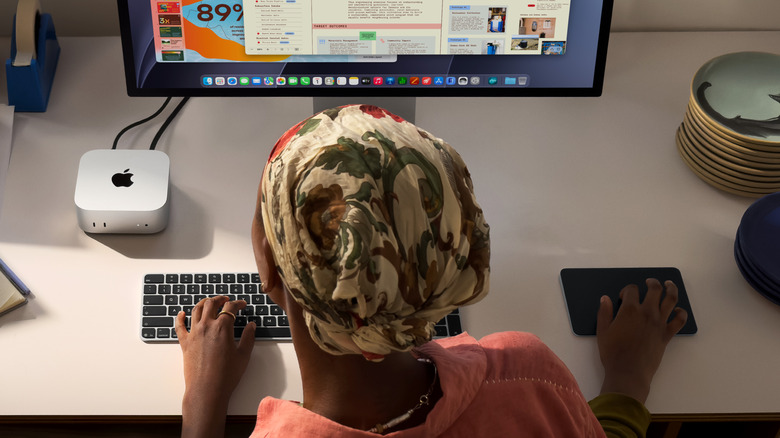 Person uses Apple Mac Mini with M6 chip alongside Apple display and Magic Keyboard