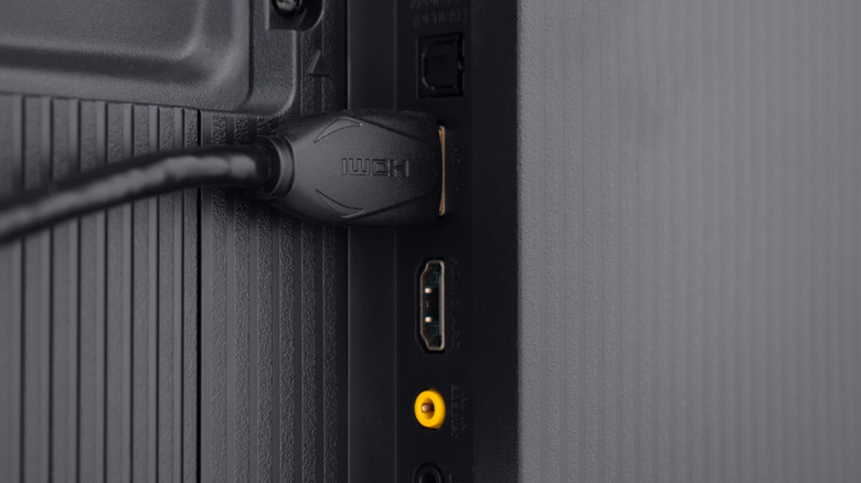 An HDMI cable plugged into the back of a TV, alongside various other ports.