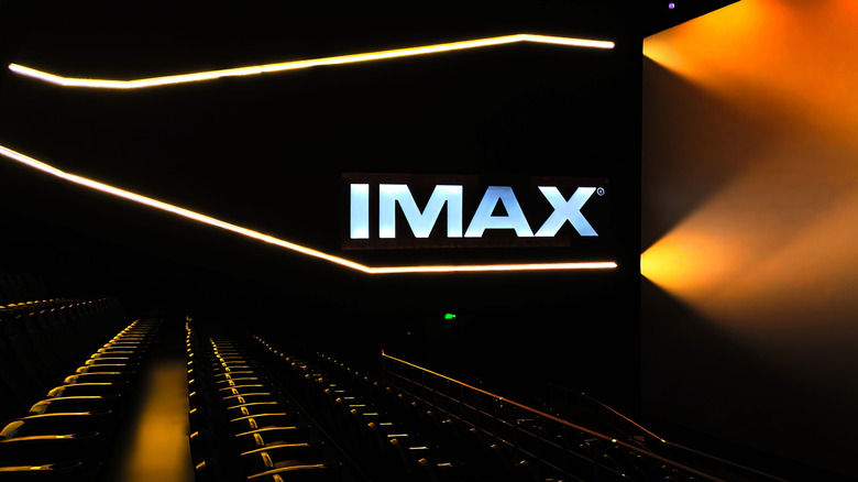A lit-up IMAX logo in a movie theater screen room.