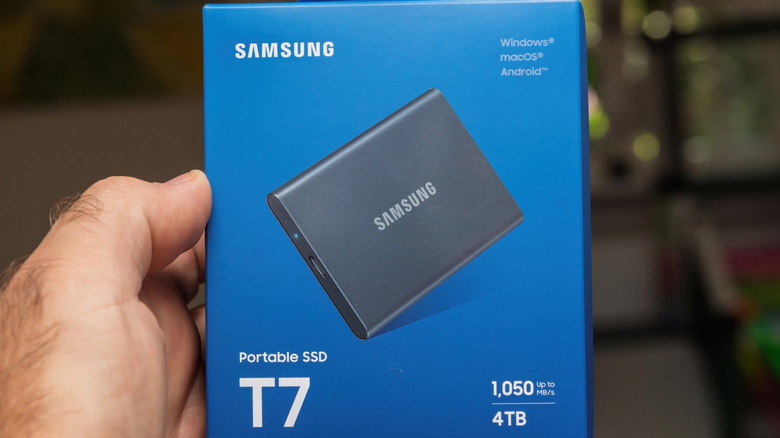A hand holding a Samsung portable SSD box.