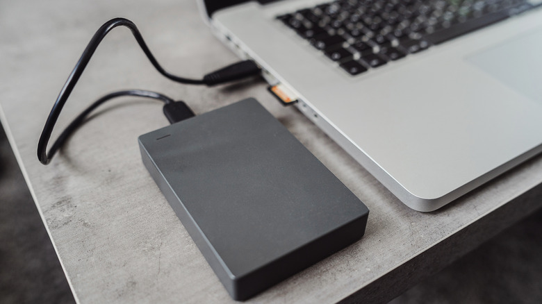 An external hard drive plugged into the side of a laptop.