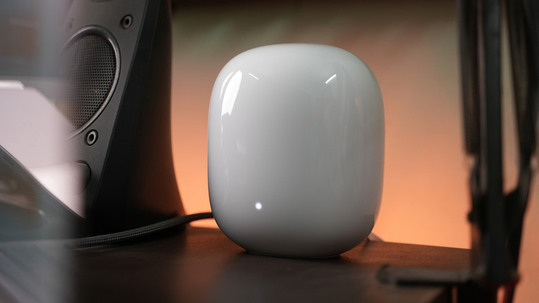 A Nest Wifi Pro router illuminated on a desktop.