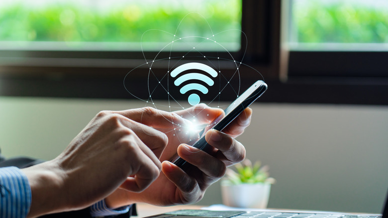 A close up of a pair of hands holding a pair of phone, where a Wi-Fi graphic appears.
